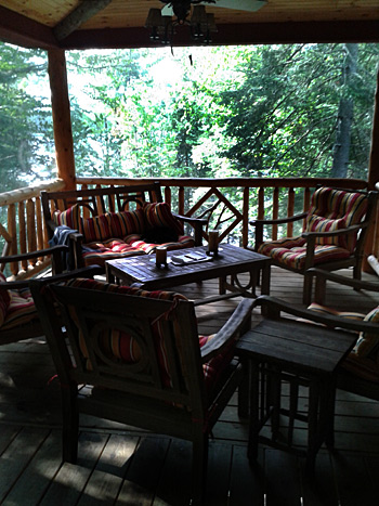 covered porch with adirondack style furniture